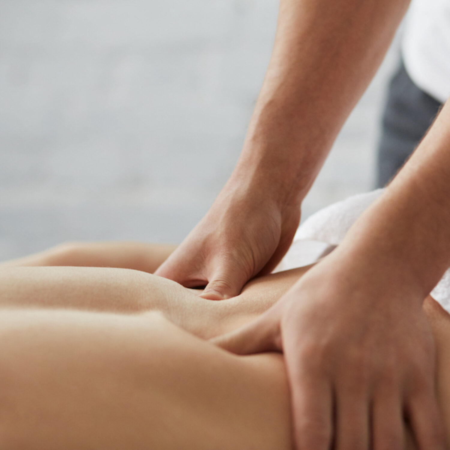 Young handsome man enjoying a back massage. Professional massage therapist is treating a male patient in apartment. Relaxation, beauty, body and face treatment concept. Home massage.